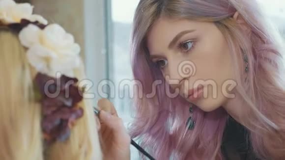 年轻的化妆师把化妆品应用在模特眼睛上视频的预览图