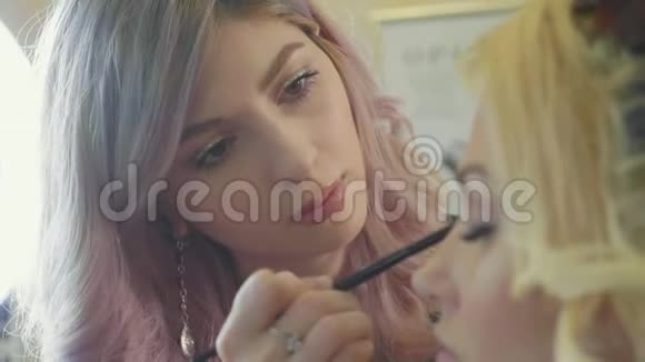 年轻的化妆师把化妆品应用在模特眼睛上视频的预览图