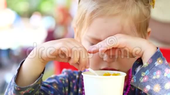 小女孩在夏季公园吃街头美食玉米旅游美食概念视频的预览图