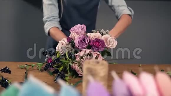 一位年轻的花店助理用丝带绑着一束花躺在她的桌子上的肖像慢镜头视频的预览图