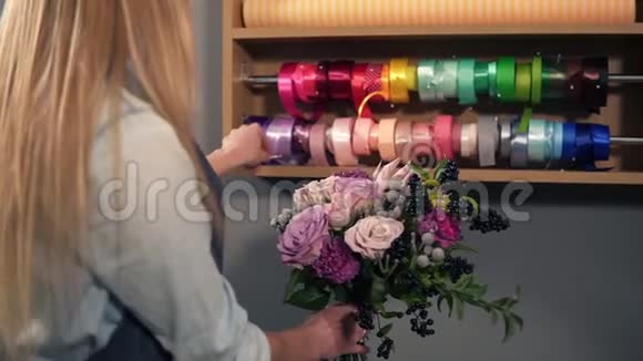女性金发花店的后视图布置现代花束并选择完美的肋骨并结合不同的视频的预览图