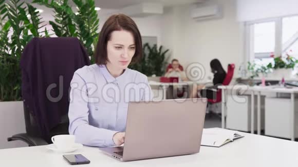 穿着蓝色衬衫的商务女性在办公室里用笔记本电脑工作视频的预览图