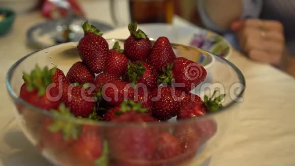 四只手近距离从玻璃碗里取出新鲜成熟的草莓视频的预览图