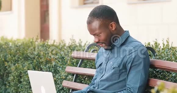 漂亮的非裔美国人在笔记本电脑上工作坐在长凳上收到好消息兴奋和高兴视频的预览图
