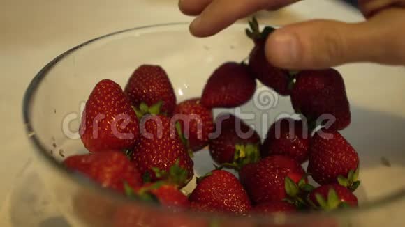 雄性手慢慢地从玻璃碗里取出新鲜成熟的草莓视频的预览图
