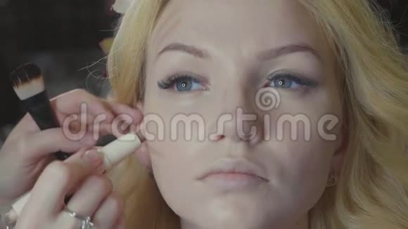 年轻的化妆师把遮瑕膏涂在模特脸上视频的预览图
