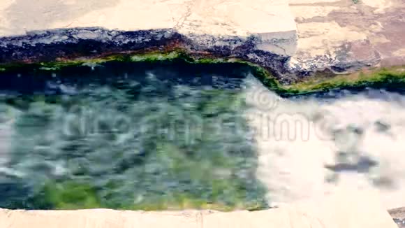 瀑布从绿色的平坦岩石上流过视频的预览图
