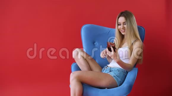 红墙背景上的女孩在电话视频短信广播中交谈视频的预览图