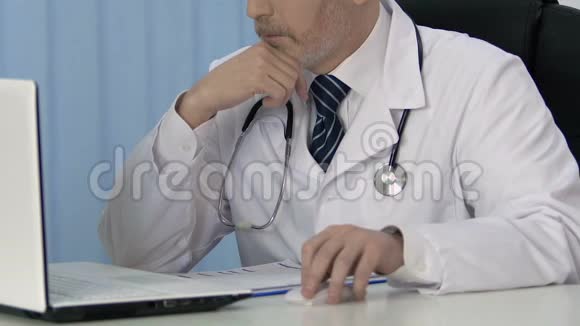 男性医生在笔记本电脑上工作在医疗记录中插入保险数据视频的预览图