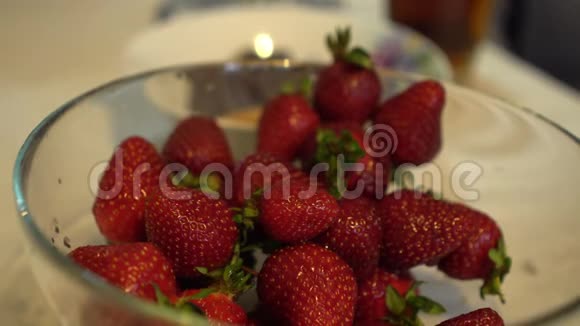 女性手从玻璃碗里取出新鲜成熟的草莓视频的预览图