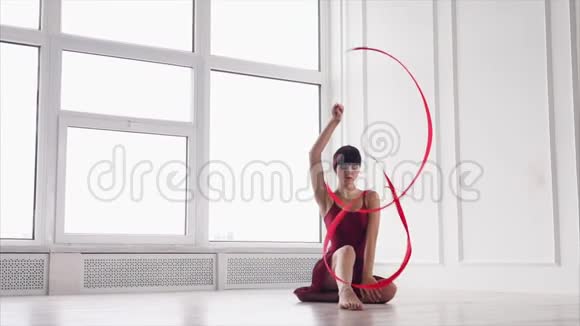 一个处理丝带的女运动员坐在地板上做伸展运动视频的预览图