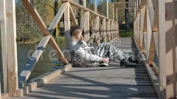 秋河附近的桥上一个女人正在看书一只黑狗正在附近散步视频的预览图