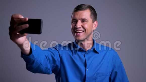 一张迷人的快乐的高加索男人的特写照片他在电话里打了个视频电话视频的预览图