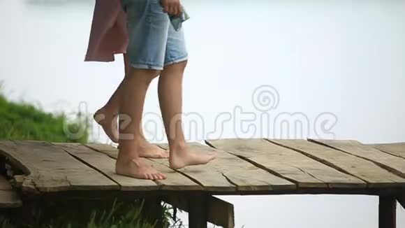 美丽的年轻夫妇走在湖边的码头上视频的预览图