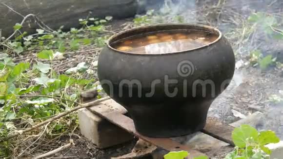 一个巨大的锅里面有一个土豆在户外的火上煮视频的预览图