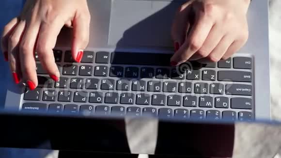 夏天海边特写在女性手上用鲜红的指甲在笔记本电脑键盘上打字工作视频的预览图