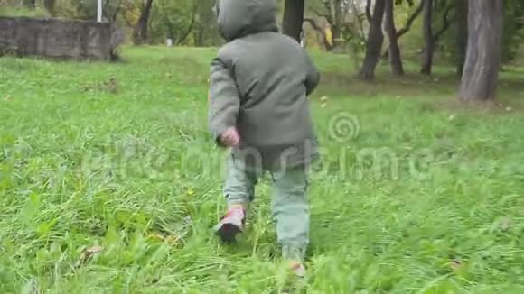 两岁的男孩在秋天的森林里奔跑公园慢动作视频的预览图