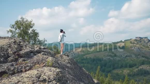 女摄影师在镜头上拍摄一幅山景照片视频的预览图