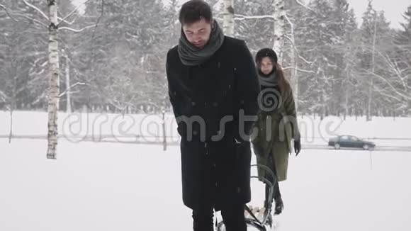 一对相爱的夫妇正带着雪橇在树林里散步视频的预览图