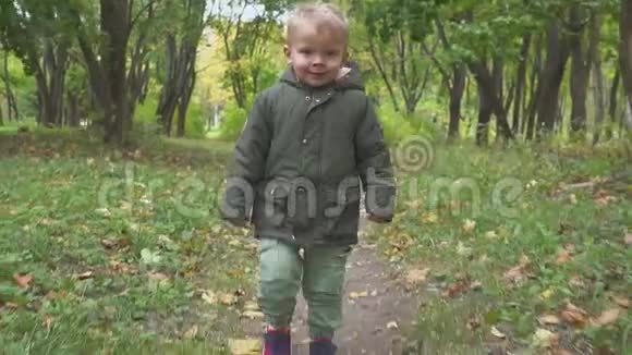 两岁的男孩在秋天的森林里奔跑公园慢动作视频的预览图
