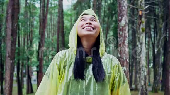 穿黄色雨衣站在雨中的快乐亚洲女人的肖像视频的预览图