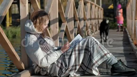 秋河附近的桥上一个女人正在看书一只黑狗和一个女孩在附近散步视频的预览图