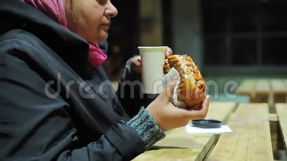 饥饿的成年妇女在慈善活动中喝茶和吃热狗快餐视频的预览图