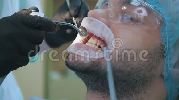 医生和病人在牙科办公室用唇扩张器关闭清洁和冲洗牙齿视频的预览图