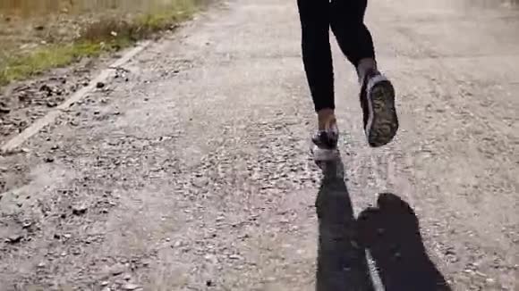 苗条的女人在阳光明媚的日子里在跑道上慢跑后景视频的预览图
