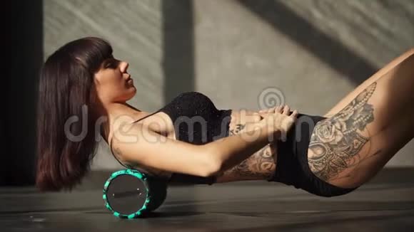 一个女人用滚筒来做背部肌肉的运动它们会使肌肉变暖视频的预览图