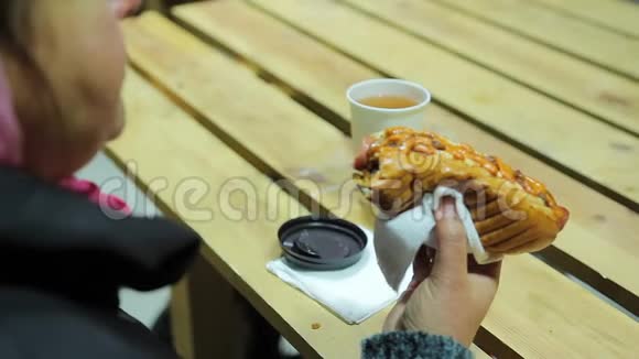 垃圾食品丰满的女人吃脂肪热狗和喝热茶超重视频的预览图