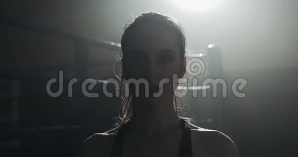 疲惫的女拳击手站在拳击台上看镜头的肖像视频的预览图