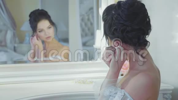 女孩在豪华的室内镜前戴着耳环动作缓慢视频的预览图