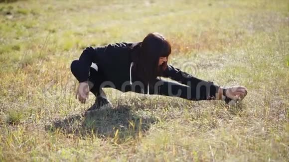 在阳光明媚的日子里年轻女子在田里做伸展腿的运动视频的预览图