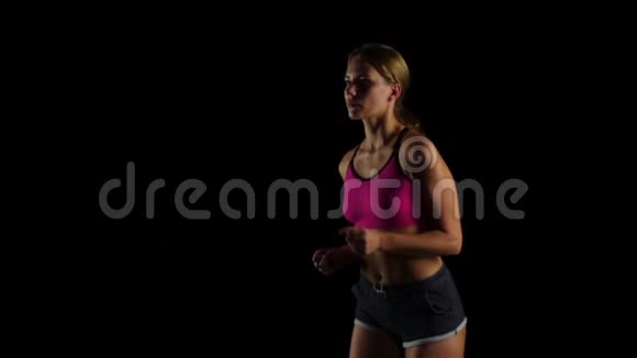 金发女运动员在黑色背景下跑步慢动作视频的预览图