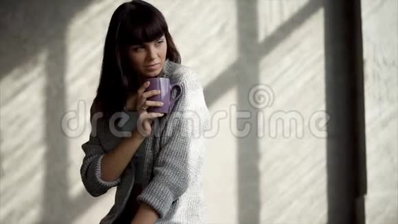 浪漫体贴的年轻女子坐在家里端着一杯茶视频的预览图