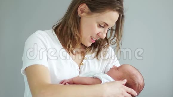 一个中年妇女正在摇动她刚出生的婴儿轻轻地握住他的手代孕母亲体外受精视频的预览图