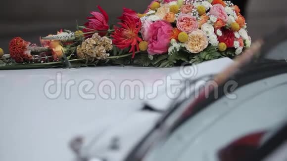 白色婚礼车白色鲜花和紫色丝带挂在汽车上视频的预览图