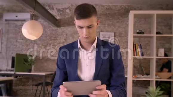 年轻的集中商人在平板电脑上观看在镜头下观看交流观念商业观念视频的预览图