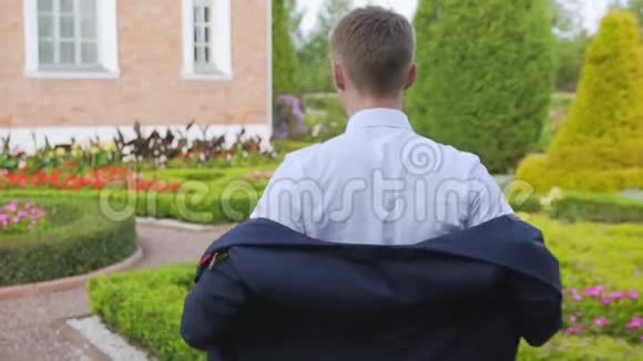 在美丽的花园里穿着西装夹克的年轻人视频的预览图