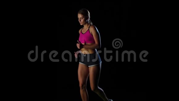 健身女人在黑色背景下跑步时低下头慢动作视频的预览图
