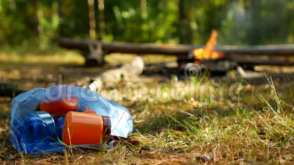 一袋塑料瓶的垃圾躺在草地上一场大火燃烧户外娱乐人们没有带走垃圾视频的预览图