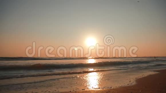 夕阳落在海边的沙滩上海浪慢慢溅在沙滩上视频的预览图
