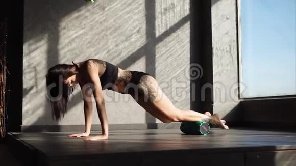 有纹身的女人在健身俱乐部用滚筒来热身肌肉视频的预览图