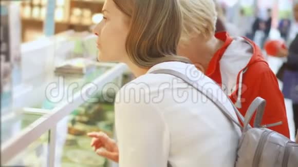 老太太和女儿在商场购物站在那里看着玻璃箱讨论购买事宜视频的预览图
