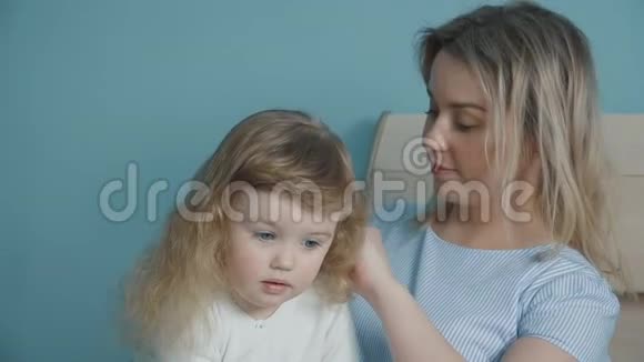 母亲梳着她可爱的小女孩的头发视频的预览图