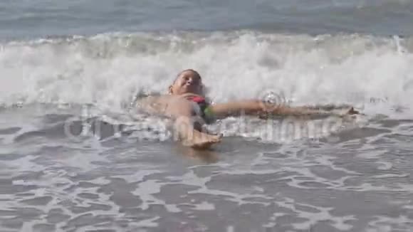 宝贝在海滩上在海浪中在金沙上玩冲浪的男孩头盖着孩子的波浪视频的预览图