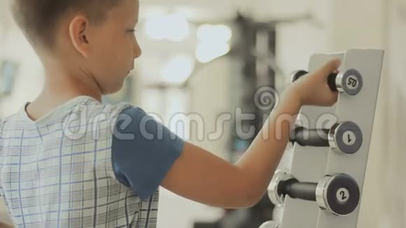 这个男孩选择哑铃作为他在健身房的训练视频的预览图