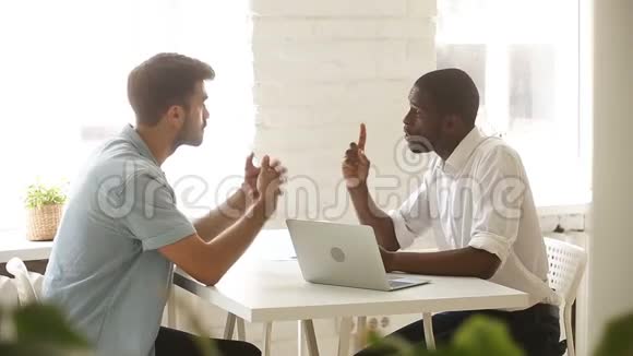非裔美国人和白人商人在办公室桌上握手视频的预览图