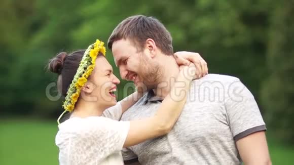 一对恩爱夫妻的肖像男人和女孩轻轻地拥抱和笑一个女人头上戴着一个蒲公英花圈视频的预览图